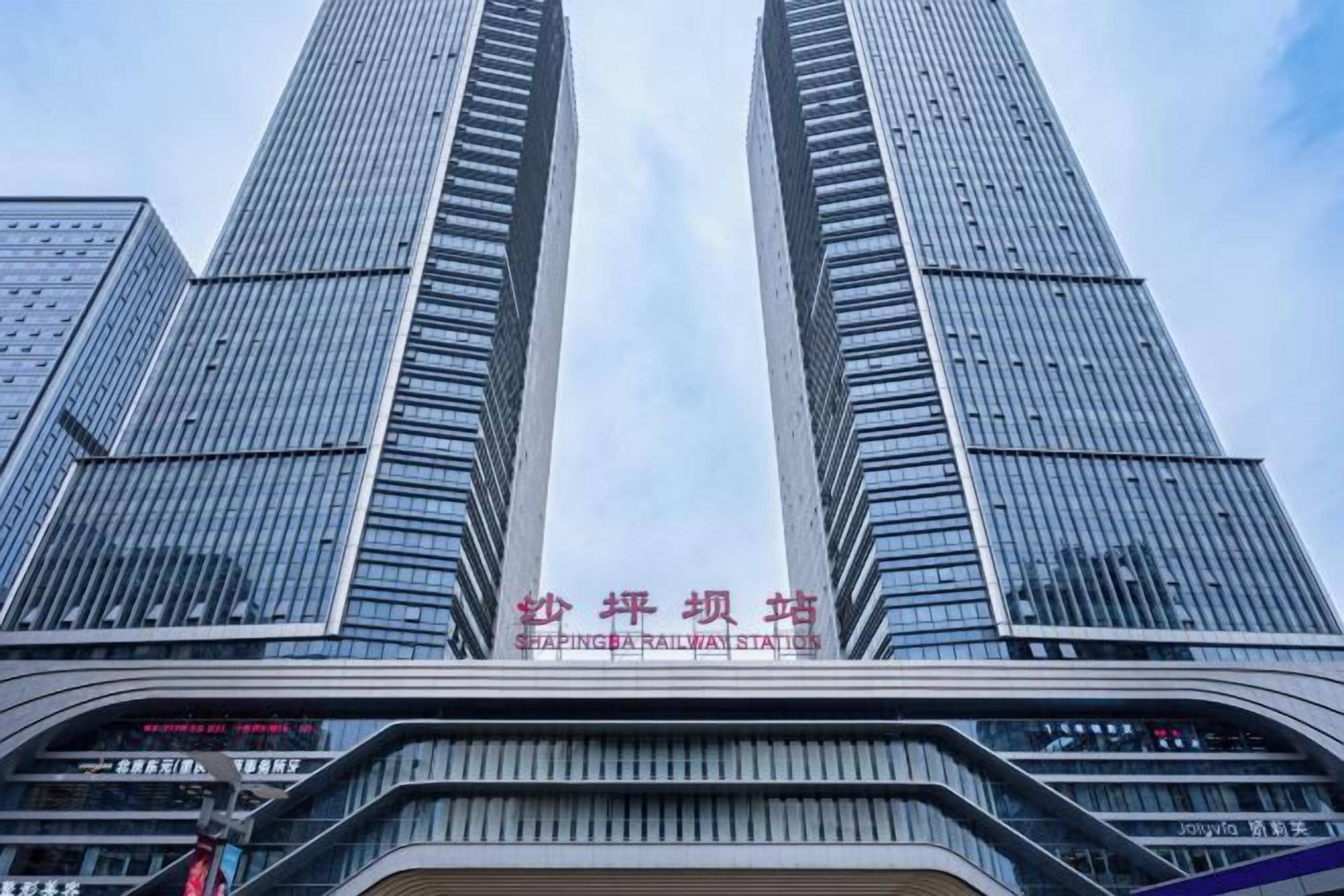 A tall building with a modern glass facade and a sign indicating a railway station.
