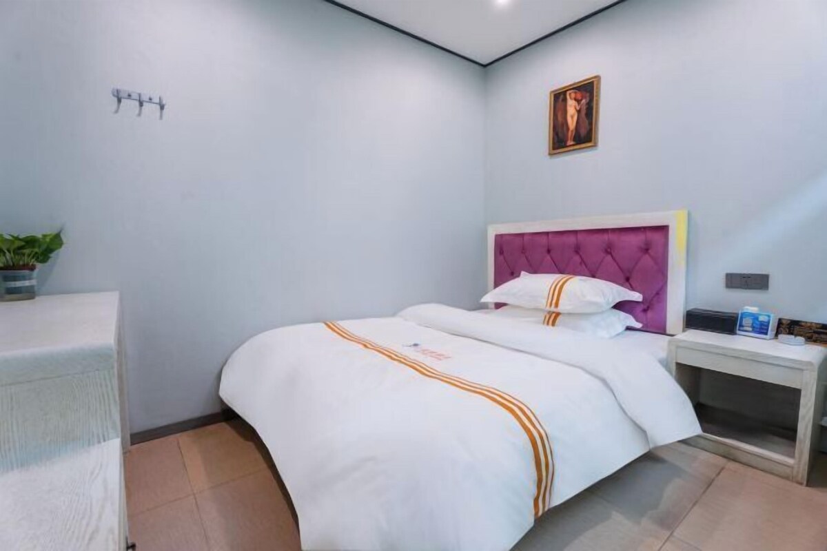 A neatly arranged hotel room with a bed, bedside table, and a small potted plant.