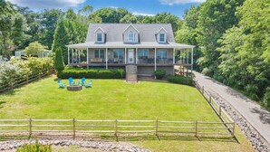 A large house with a covered porch, a lawn, and a fence.