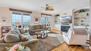 A living room with a fireplace, a television, and a large window.