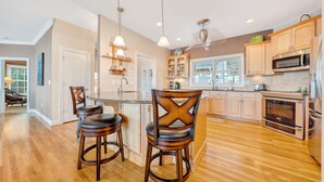 A modern kitchen with wooden cabinets, stainless steel appliances, and a central island with bar stools.