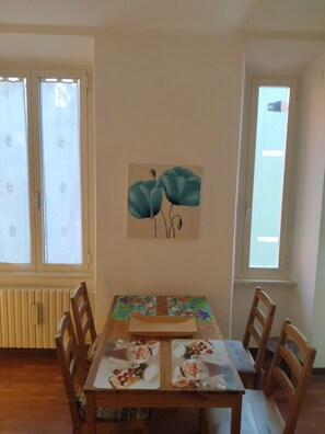 Un coin repas comprenant une table, des chaises, un radiateur et un tableau accroché au mur.