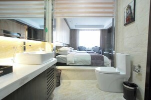 Una habitación de hotel pequeña con cama, lavamanos, inodoro y espejo.