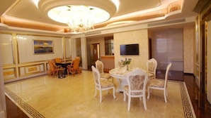 A spacious dining area with a round table and chairs, a chandelier, and a television on the wall. - Kai Bin Hotel (Baiyin)