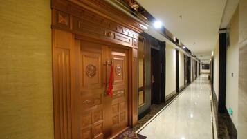 A hallway with wooden doors, a marble floor, and a carpeted entrance.