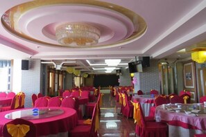 Une salle de banquet avec des tables rondes, des chaises et un lustre.