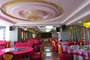 Un salón de banquetes con mesas redondas, sillas y una lámpara de araña.