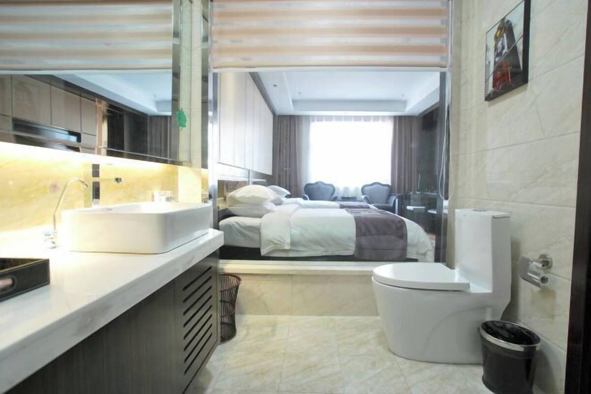 Habitació d'hotel senzilla amb llit, vàter, rentaplat i mirall.