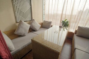 A room with a wicker sofa, a glass coffee table, and sheer curtains. - Kai Bin Hotel (Baiyin)