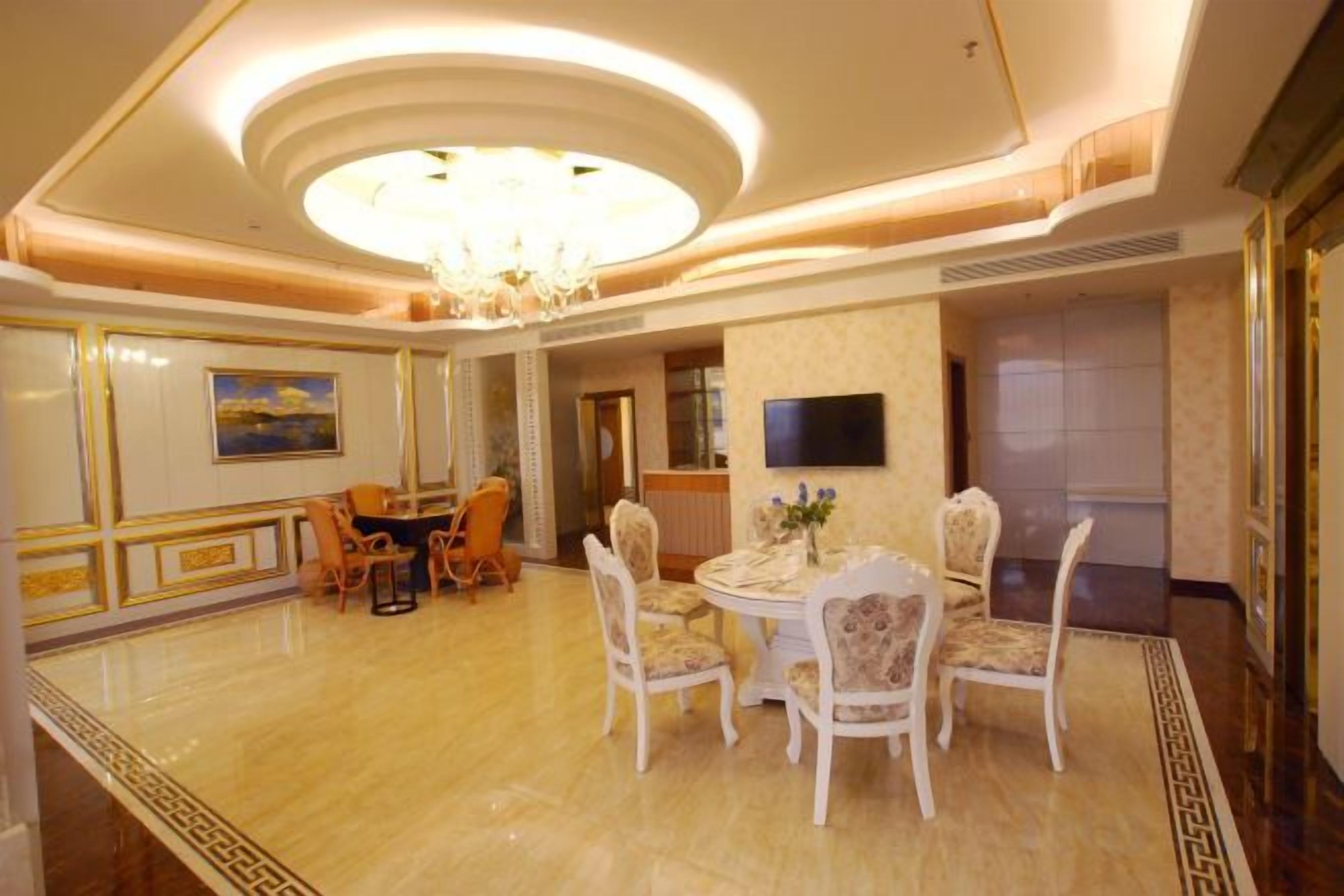 A dining area with a chandelier, a round table, and chairs.