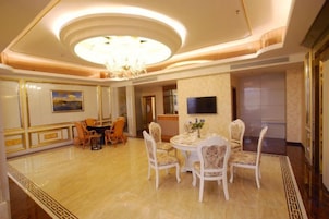 Uma sala de jantar com lustre, mesa redonda e cadeiras.