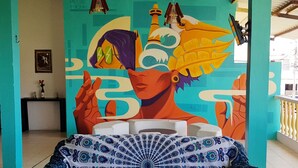 A room with a colorful mural, a patterned sofa, and a small table with a magazine.