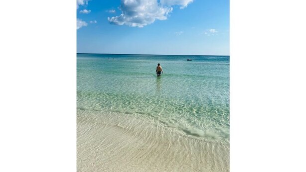 A beach with clear shallow water and a person standing in the distance. - Serene Home with PRIVATE Pool - Near Beaches - Dog Friendly - Firepit&Large Yard (Freeport)