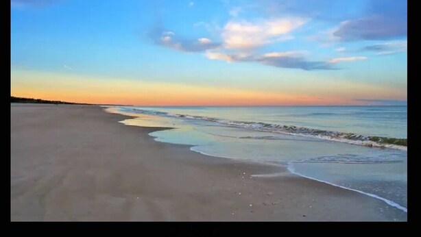 A beach with a wide sandy shore and gentle waves. - Lake house scenic view with close proximity to the beach and necessities (Jacksonville)