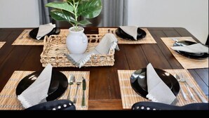 A dining table set with black plates, silverware, and a white vase with green leaves. - Lake house scenic view with close proximity to the beach and necessities (Jacksonville)