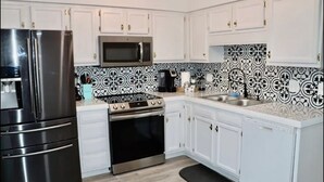 A kitchen with white cabinets, a stainless steel refrigerator, a microwave, an oven, and a sink. - Lake house scenic view with close proximity to the beach and necessities (Jacksonville)