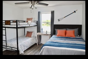 A room with a bunk bed, a single bed, a desk, and a ceiling fan. - Lake house scenic view with close proximity to the beach and necessities (Jacksonville)