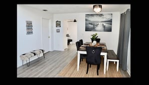 A dining area with a wooden table, black chairs, and a bench. There is a chandelier above the table and a large black and white photograph on the wall. - Lake house scenic view with close proximity to the beach and necessities (Jacksonville)