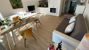 A modern living room with a wooden dining table, a sofa, and a TV.