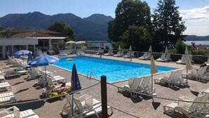 A pool area with lounge chairs and umbrellas, surrounded by mountains.