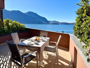 A terrace with a table set for two, overlooking a body of water and mountains. - Barbara apartment with lake view in Ghiffa (Ghiffa)