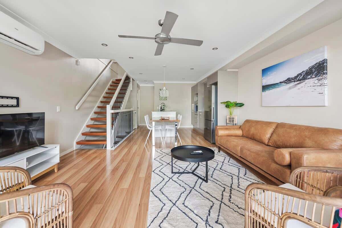 A modern living room with a sofa, TV, and a staircase.