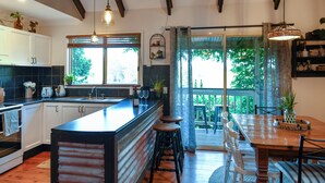 Una cocina moderna con una isla grande, taburetes de madera y un comedor con mesa y sillas.