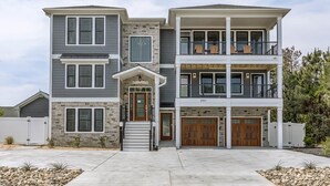 A two-story residential building with a stone facade, a front porch, and a balcony on the upper level. - Happy As a Clam  | 230 ft to the beach | Private Pool, Hot Tub, Dog Friendly (Virginia Beach)