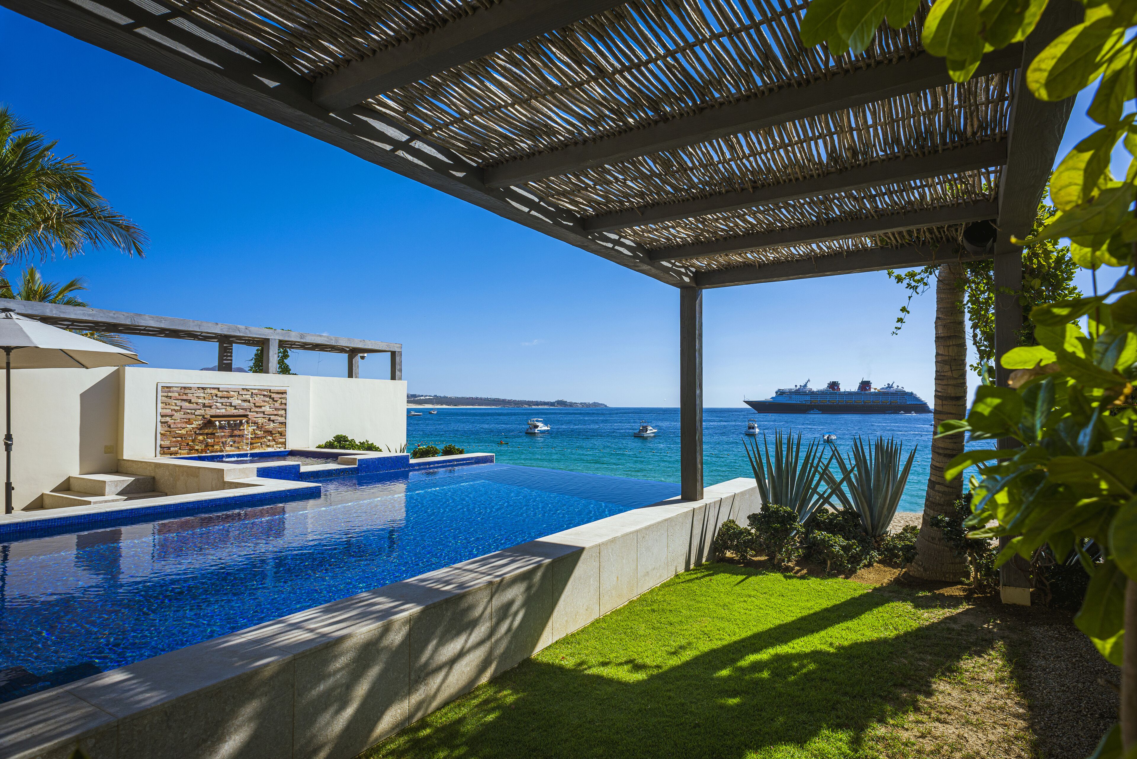 Ein Pool mit freiem Blick auf das Meer und einem Kreuzfahrtschiff in der Ferne.