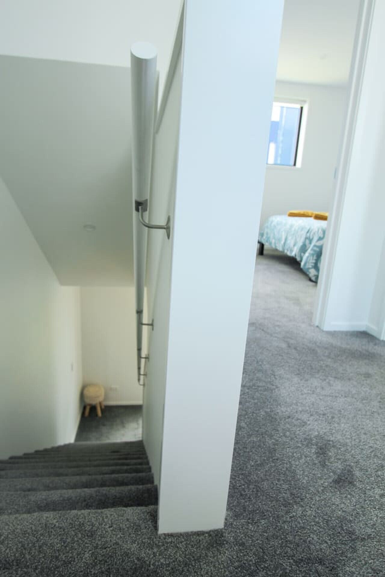 A staircase leading to a bedroom with a bed and a window.