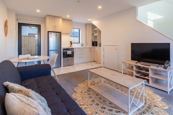 Un espace de vie moderne comprenant un canapé, une table basse, un téléviseur à écran plat et un coin repas avec une table et des chaises.