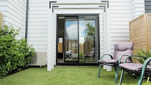 A patio with a sliding glass door, a small lawn, and a seating area with two chairs.