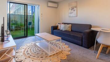A modern living room with a grey sofa, a white coffee table, and a round woven rug.