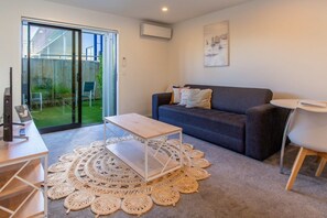 Un salon moderne avec un canapé gris, une table basse blanche et un tapis rond en fibres tressées.