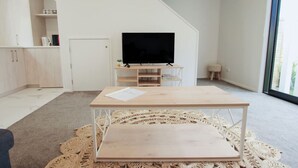 A modern living room with a flat-screen TV, a wooden coffee table, and a cozy knitted rug.