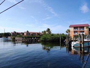 A waterfront hotel with a dock, palm trees, and a clear sky.