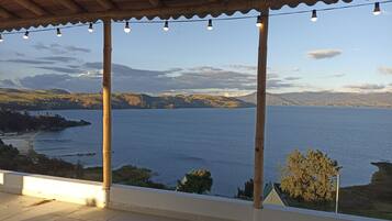 A balcony with a view of a lake and distant hills.