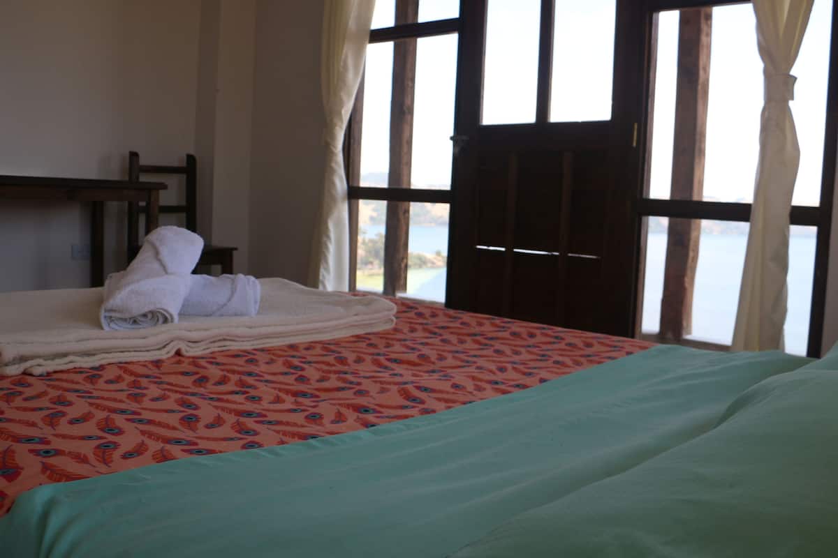 Quarto de hotel com cama, janela com cortinas e vista para o exterior.