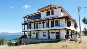 A two-story building with a balcony, located near a body of water with a clear sky. - Hotel Eliseo-Playa Blanca lago de Tota  (Tota)
