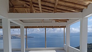 A spacious balcony with a tiled floor and a bamboo ceiling, offering a view of the sea and distant hills. - Hotel Eliseo-Playa Blanca lago de Tota  (Tota)