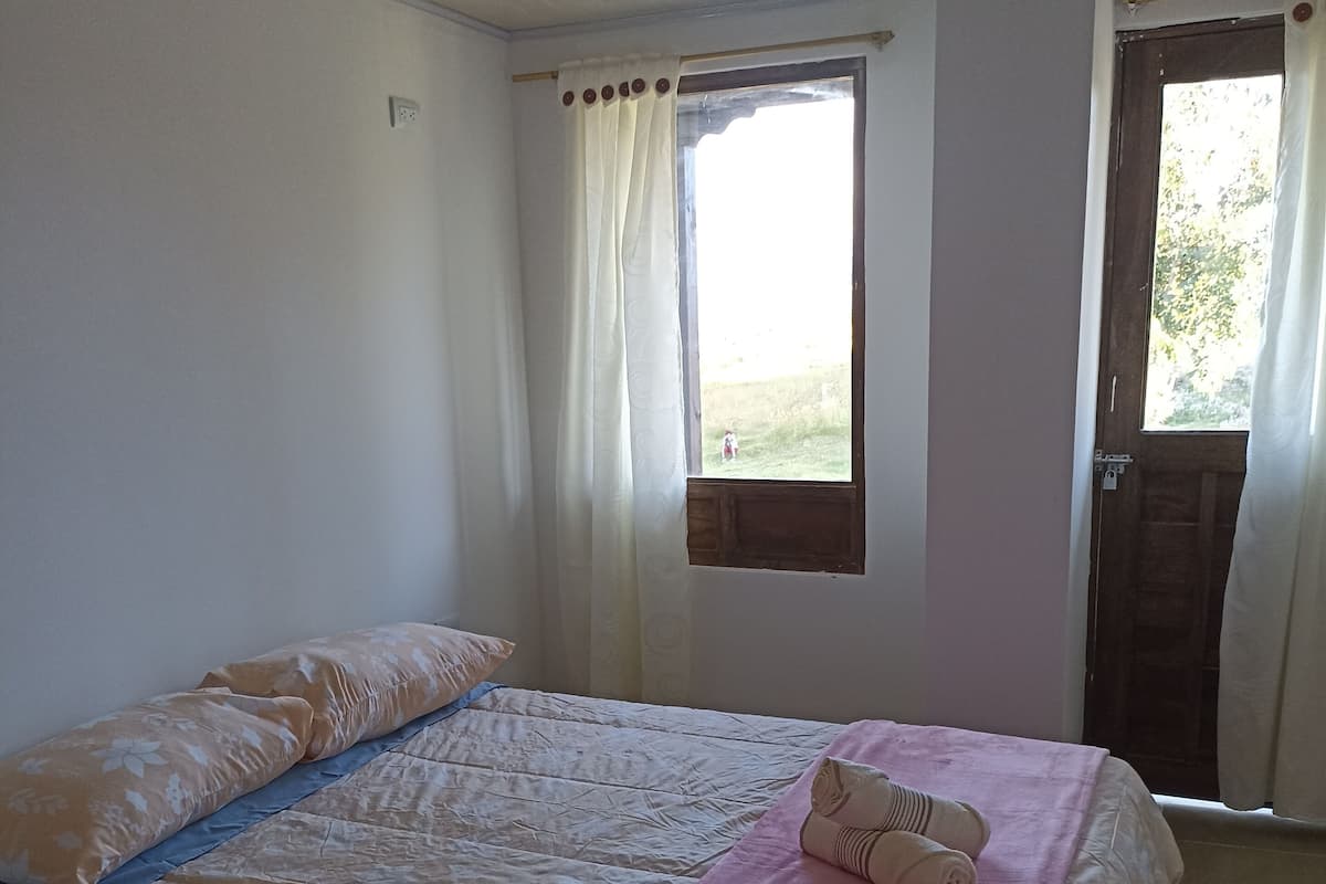 Quarto com cama, janela e porta.