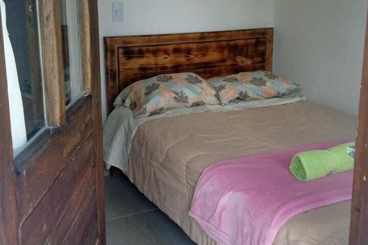 Una camera da letto con un letto di legno, una finestra e pavimento piastrellato.
