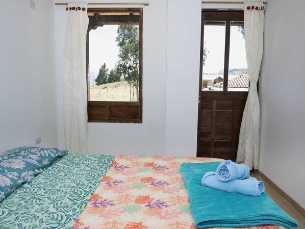 A bedroom with a bed, a window, and a door.