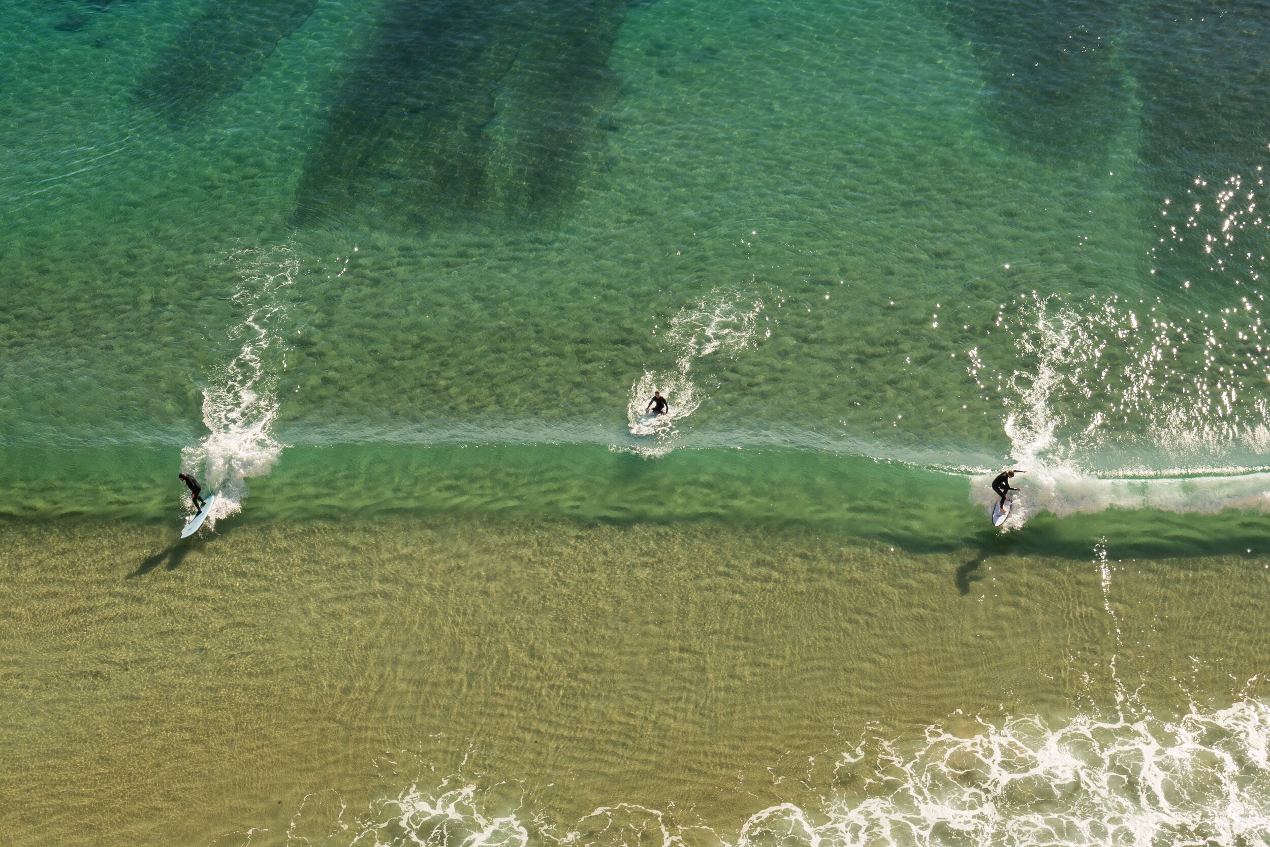 Vista aérea de una playa con agua cristalina y olas.
