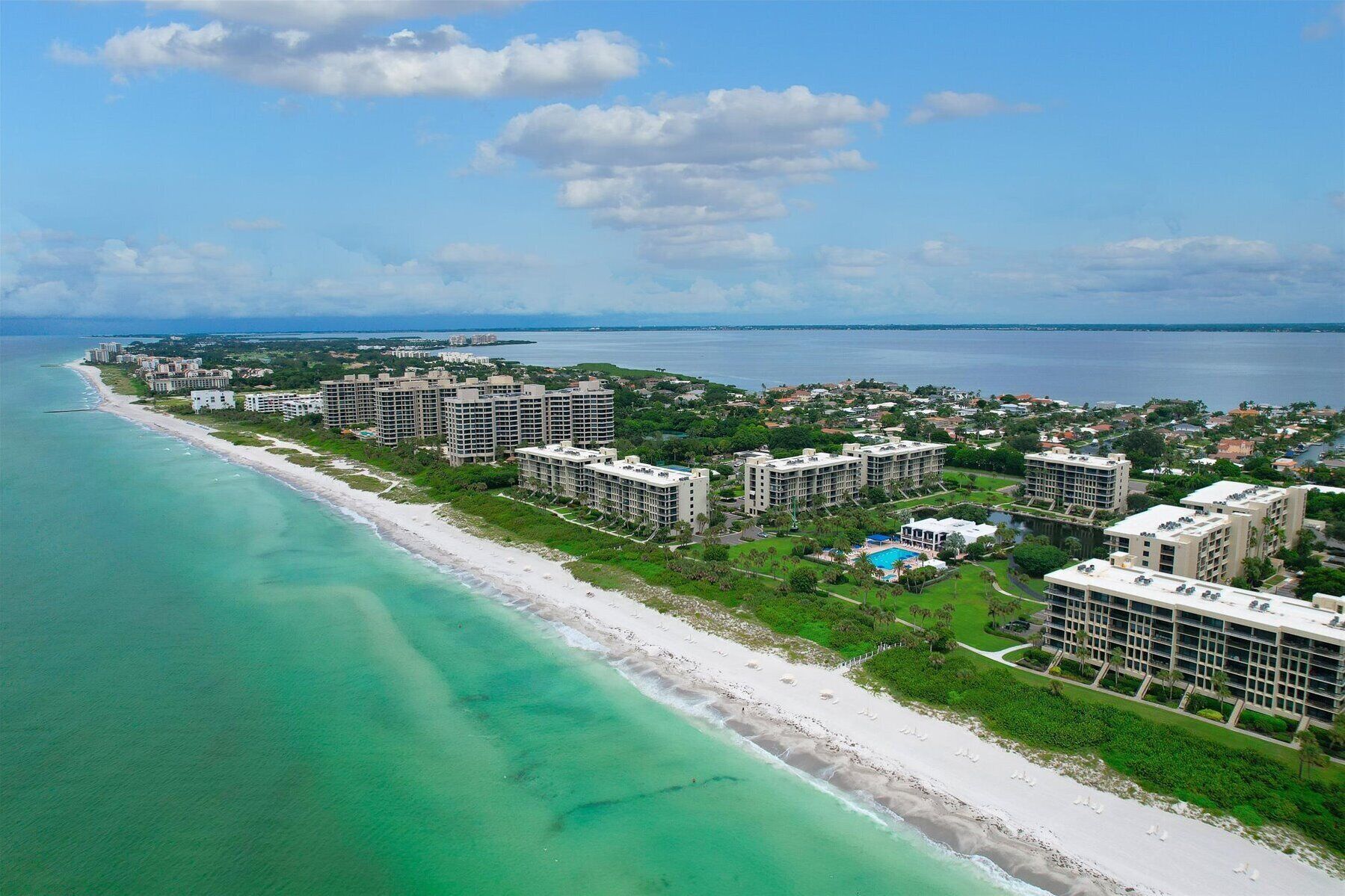 An aerial view of a coastal hotel area with beachfront properties and a swimming pool.