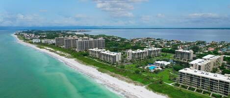 An aerial view of a coastal hotel area with beachfront properties and a swimming pool.