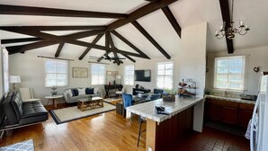 A spacious living area with a high ceiling, wooden beams, a dining table, and a kitchen with a large island. - San Diego Old Town Family-sized Apartment with Patio (San Diego)