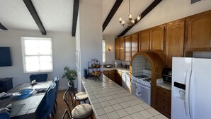 A kitchen with wooden cabinets, a tiled countertop, a gas stove, and a refrigerator. - San Diego Old Town Family-sized Apartment with Patio (San Diego)
