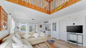 A modern living room with a wooden staircase, a beige sofa, a wooden coffee table, and a flat-screen TV. - 7557-Turtle's Pace - Avon Canalfront Retreat With Private Dock (Avon)