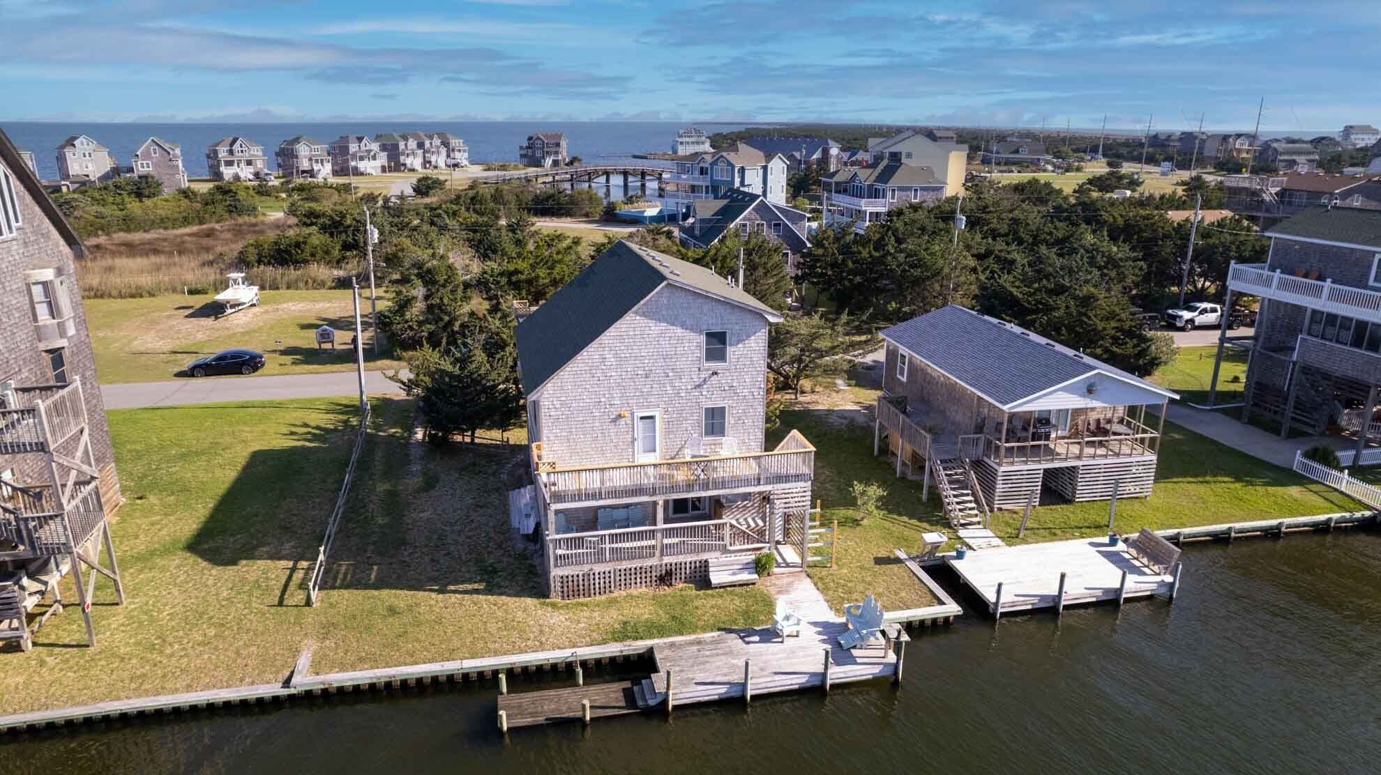 A waterfront property with a dock, a large house with a balcony, and a smaller building with a deck.